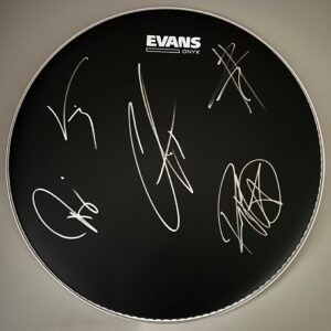 A black drumhead with the brand name 'EVANS ONYX' printed on top. The surface is adorned with multiple white signatures from various artists from Mothionless in White, covering different sections of the drumhead.