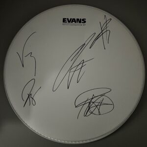 A white drumhead with the logo "EVANS G1" printed at the top. The drumhead features multiple signatures in black ink, scrawled across its surface.